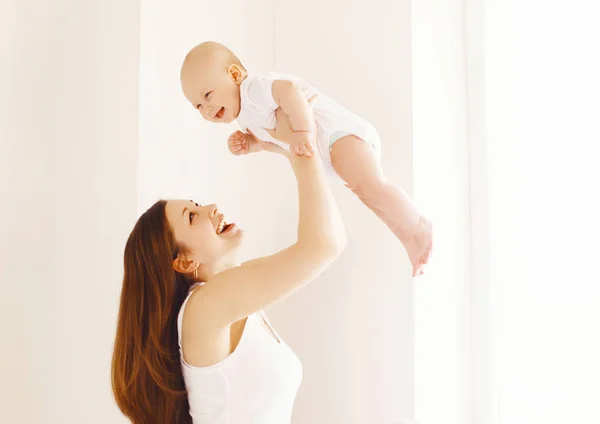 Feliz sorrindo mãe brincando com o bebê em casa na sala branca — Fotografia de Stock