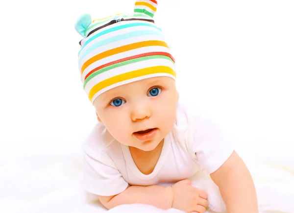 Portrait closeup of baby in colorful hat crawls on a white backg — Stock Photo, Image