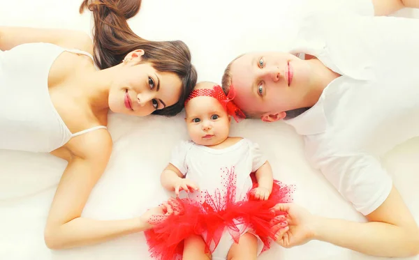 Portrait happy family mother, father and baby lying on the bed a — Stock Photo, Image