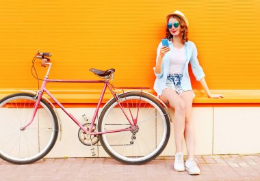 Retro bisiklet o ile akıllı telefon kullanan yaz gülümseyen genç kadın