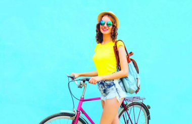 Mavi renkli bir arka plan üzerinde bisiklet ile yaz gülümseyen kadın