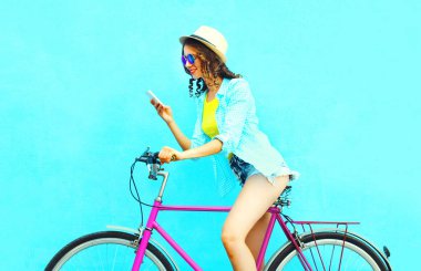 Kadın üzerinde renkli bir blu retro bisikletle Smartphone kullanarak yaz