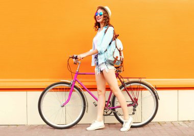 Turuncu renkli arka plan üzerinde bisiklet ile genç kadın yaz