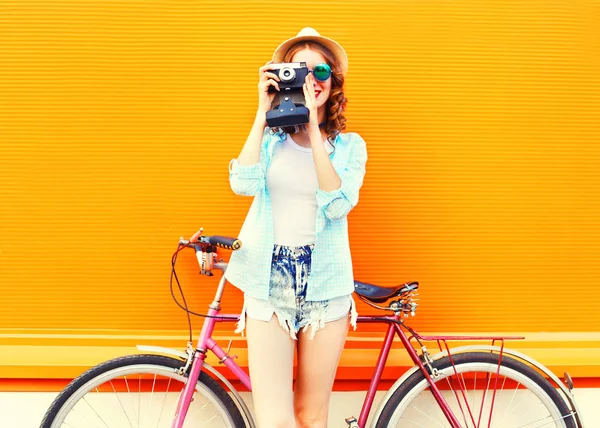 Летняя модница с ретро-камерой и велосипедом на цветном — стоковое фото