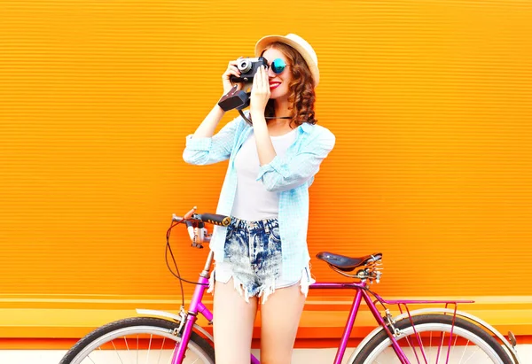 Verão mulher bonita com câmera retro e bicicleta em um colorido — Fotografia de Stock