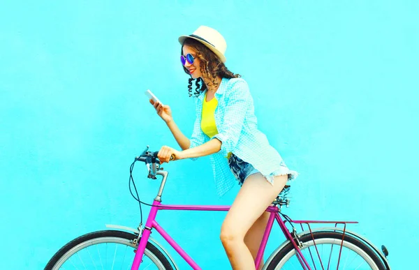 Mulher de verão usando smartphone na bicicleta retro em um blu colorido — Fotografia de Stock