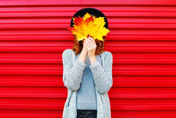 Модний осінній портрет жінки ховає її обличчя жовтим кленовим листям — стокове фото