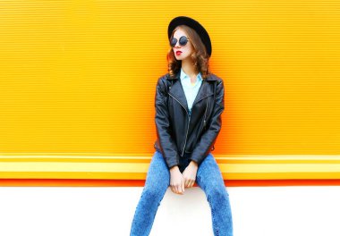 Siyah kaya ceketli bir oran üzerinde şehirde oturan kadın moda