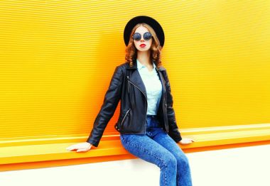 Şehirde colo üzerinde oturan siyah kaya ceketi giyen kadın moda