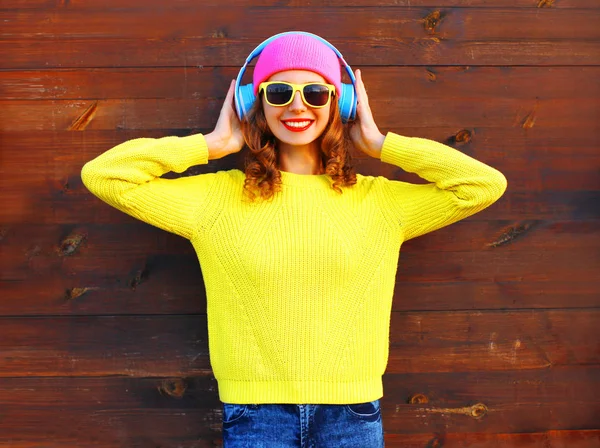 Módní usmívající se žena poslouchá hudbu ve sluchátkách, barevné p — Stock fotografie