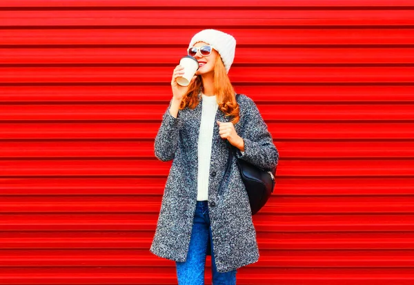 Fashion pretty woman drinks coffee wearing a coat and backpack o — Stock Photo, Image