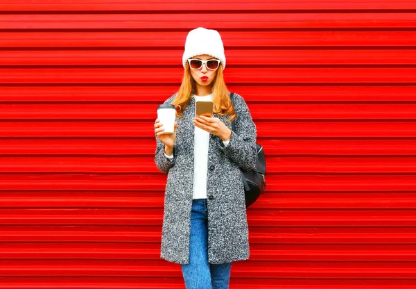 Μόδα όμορφη νεαρή γυναίκα με φλιτζάνι καφέ χρησιμοποιώντας το smartphone σε ένα — Φωτογραφία Αρχείου