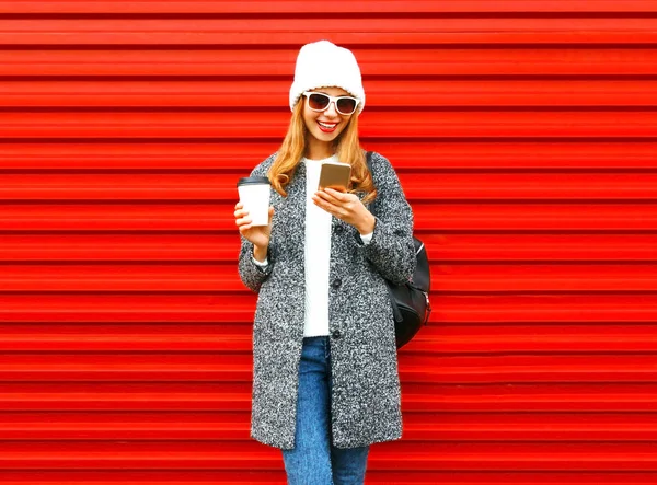 ファッション笑顔の女性が、r の上にコーヒー カップのスマート フォンを使っています。 — ストック写真