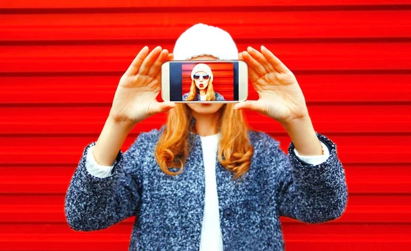 Mujer de moda toma una foto autorretrato en el teléfono inteligente en rojo — Foto de Stock