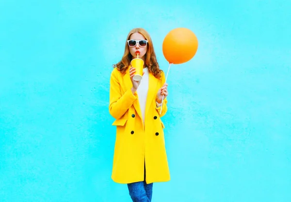 Fashion pretty woman drinks fruit juice holds orange air balloon