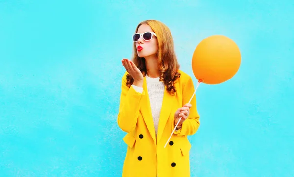 ファッション女性送信空気キスは、イエロー コートを着た o でバルーンを保持しています。 — ストック写真