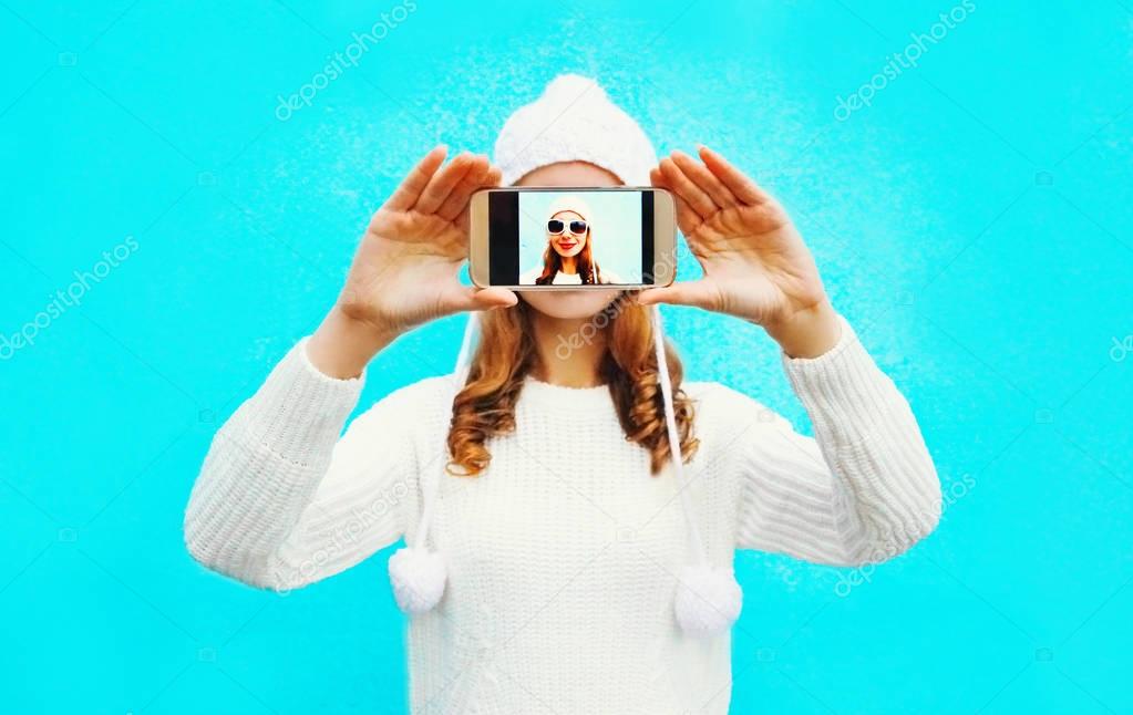 Fashion woman takes a picture self portrait on smartphone on a b