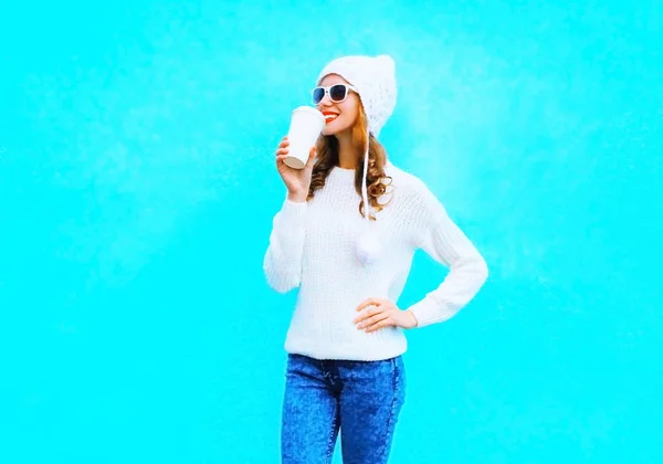 Mujer bebe café en suéter blanco, sombrero sobre un fondo azul i —  Fotos de Stock