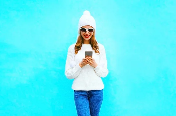 女性が白いセーター、青色表現の帽子でスマート フォンを使用してください。 — ストック写真