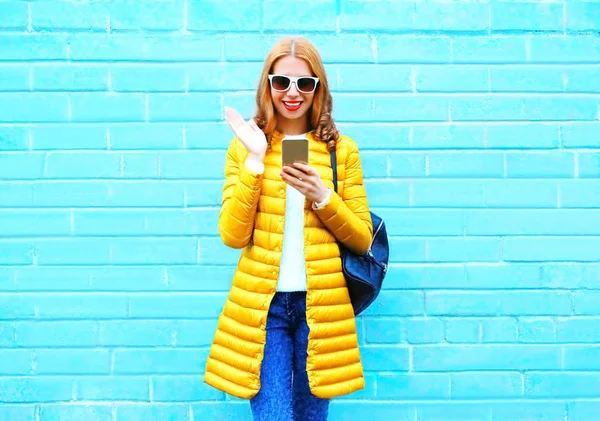 Moda rindo mulher usando smartphone em um backgrou tijolo azul — Fotografia de Stock