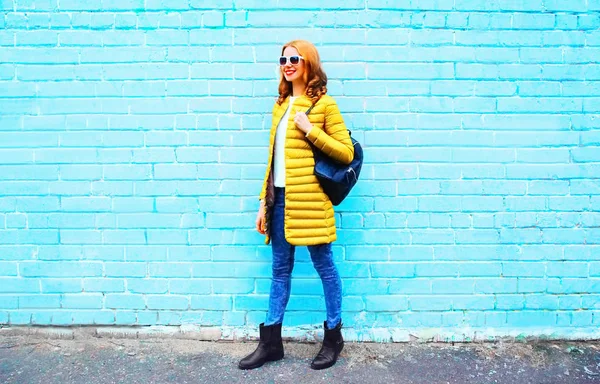 Mode hübsche Frau mit Rucksack auf einem bunten blauen Backsteinrücken — Stockfoto