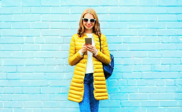 Mujer sonriente moda está utilizando el teléfono inteligente en un backgr ladrillo azul —  Fotos de Stock