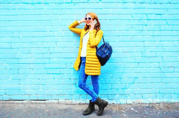 Mode leende kvinna samtalen på en smartphone på en blå tegelsten tillbaka — Stockfoto