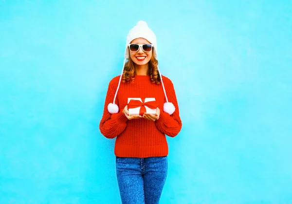 Felice sorridente giovane donna tiene in mano una scatola regalo su un dorso blu — Foto Stock