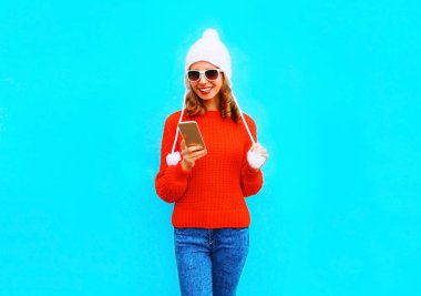 Gülümseyen kadın moda kırmızı kazaklı, şapkasını smartphone kullanarak