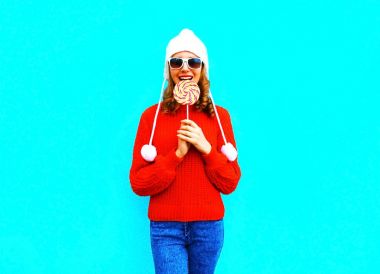 Çok gülümseyen kadın portre bir lolipop kırmızı örme sw ısırır.