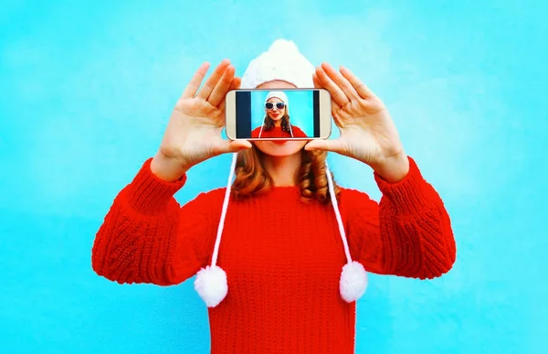 Mujer feliz toma una foto autorretrato en el teléfono inteligente en un blu — Foto de Stock