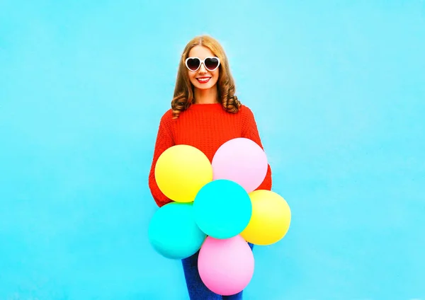 Mode hübsche Frau hält einen bunten Luftballons auf blauem Rücken — Stockfoto
