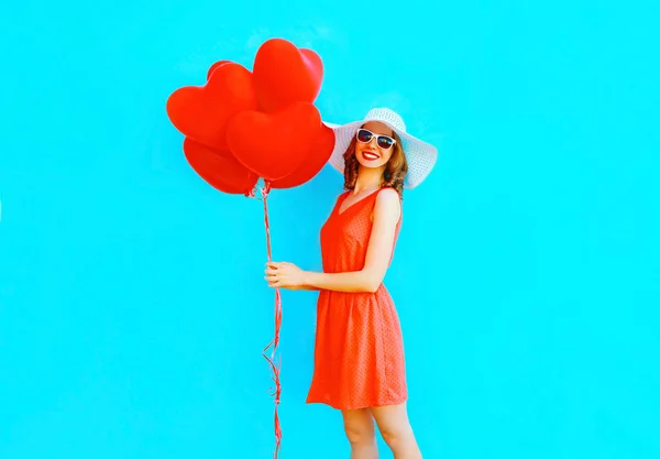 Happy smiling woman in red dress, hat, holds an air balloons hea