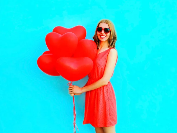 Portret szczęśliwy uśmiechający się kobieta z czerwonymi powietrza balony na ba niebieski — Zdjęcie stockowe