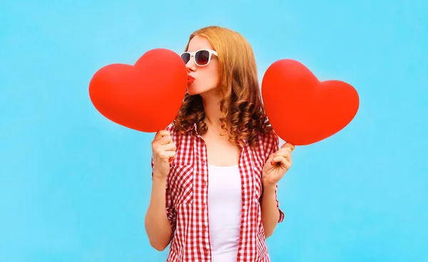 pretty woman kisses a red air balloon in the shape of a heart on