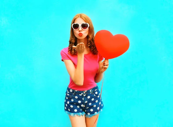 Mujer bonita envía un beso de aire sostiene un globo rojo en la forma —  Fotos de Stock