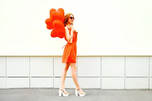 Usmívající se žena chodí s červeným vzduchové bubliny v tvaru hea — Stock fotografie