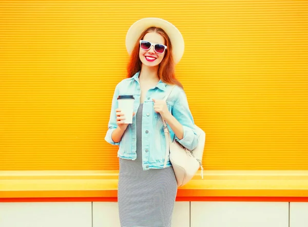Модная симпатичная улыбчивая женщина с чашкой кофе на оранжевом рюкзаке — стоковое фото