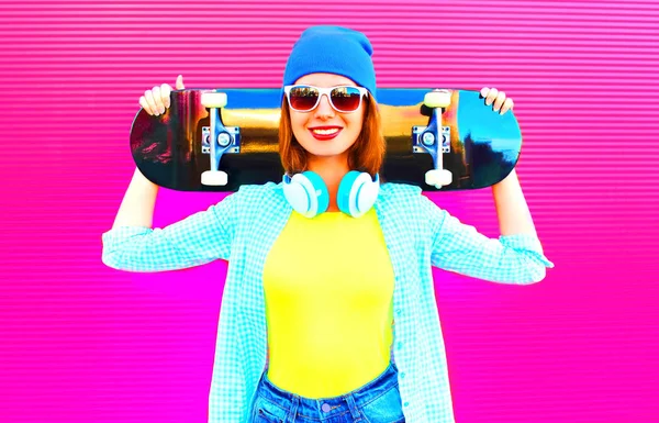 Mode vrij lachende vrouw met een skateboard in de stad op pi — Stockfoto