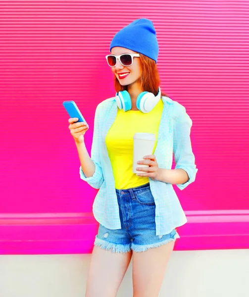 Uśmiechający się młoda kobieta moda przy filiżance kawy, za pomocą smartfona o — Zdjęcie stockowe