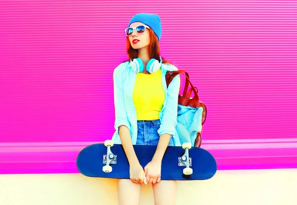 De jonge vrouw mode met een skateboard in de stad op een roze rug — Stockfoto