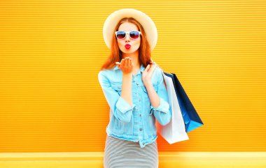 Bir hava öpücük alışveriş torbaları s tutan genç kadın moda gönderir