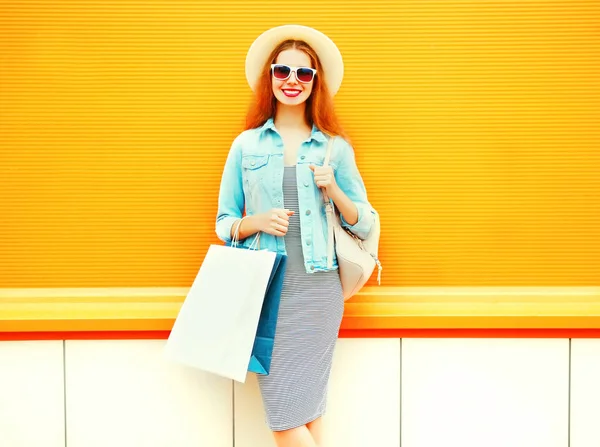 Moda mulher sorridente com sacos de compras, chapéu de palha em laranja ba — Fotografia de Stock