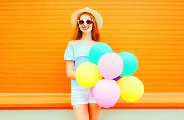 Turuncu ba üzerinde bir hava renkli balonlarla gülümseyen kadın moda