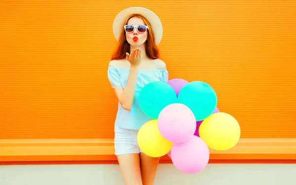 Mujer de moda envía un beso de aire con globos en fondo naranja —  Fotos de Stock
