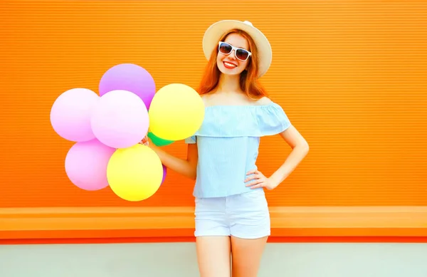 Mujer de moda con un aire globos de colores sobre fondo naranja —  Fotos de Stock