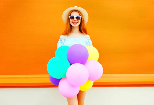 Усміхнена жінка з повітряними барвистими кульками на помаранчевому фоні — стокове фото