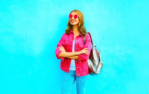Модная симпатичная улыбающаяся женщина в розовом джинсовом пиджаке на голубой спине — стоковое фото