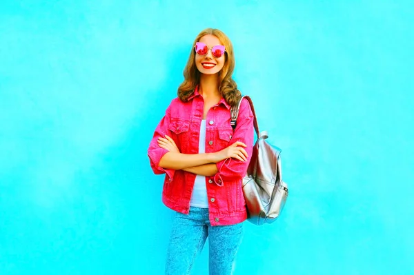 Модная улыбающаяся женщина в розовом джинсовом пиджаке на голубом фоне — стоковое фото