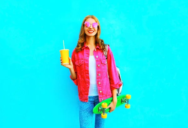 Moda donna sorridente con uno skateboard, tazza di succo di frutta in p — Foto Stock